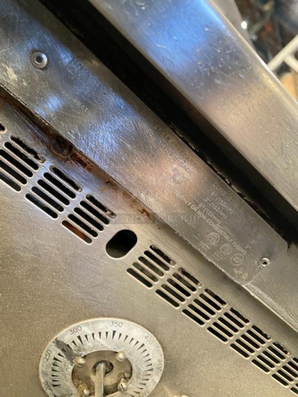 Keating stainless steel gas-powered flat griddle, countertop model with back and side splash, thermostatic control, on legs, visible wear.