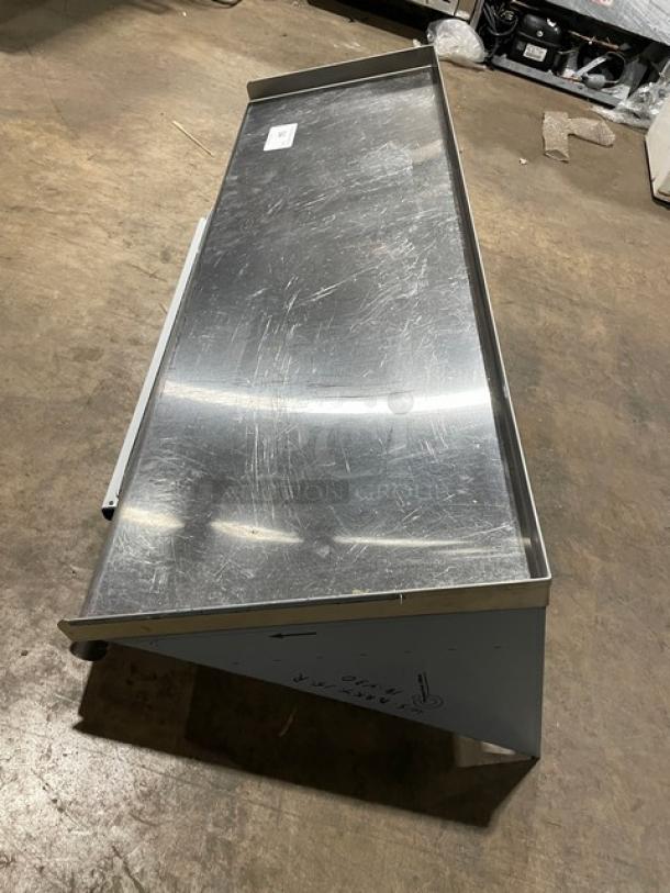 Commercial stainless steel wall-mount shelf with ticket holder. Rectangular shape, minor scratches, ideal for kitchen use.