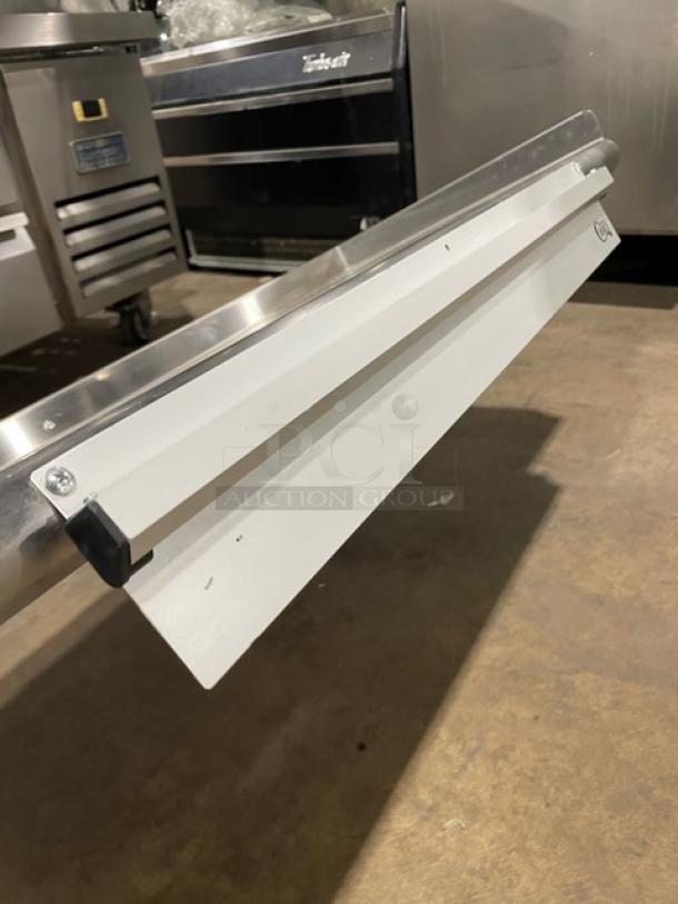 Commercial stainless steel rectangular wall-mount shelf with ticket/order holder, shown in excellent condition.