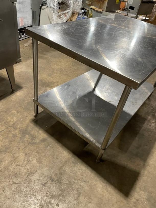 Commercial stainless steel flat worktop table with single undershelf, on legs. Appears gently used, suitable for kitchen use.