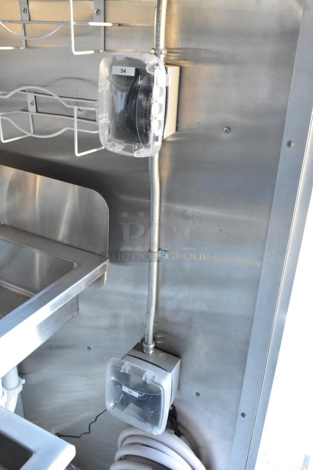 Interior of a brand new 2021 Cruising Kitchens 24' Burger King fast food trailer, showing stainless steel wall, electrical outlets, and part of a sink. Perfect for mobile kitchen use.