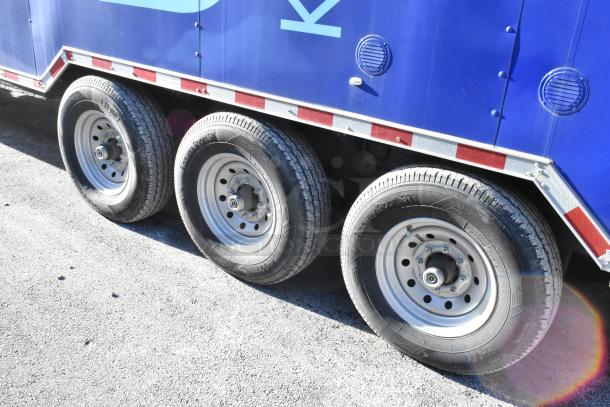 Three wheels of a new 2021 Cruising Kitchens 24' Burger King fast food trailer, showing robust tires and red accent trim.