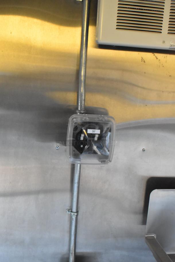Interior of 2021 Cruising Kitchens 24' trailer with visible pipe and electrical box. Features commercial equipment.