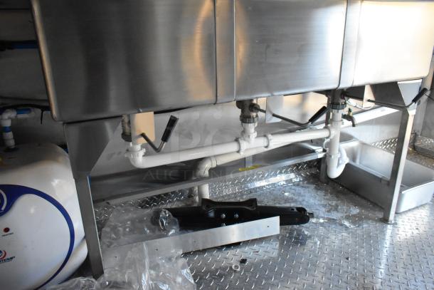 Brand new 2021 Cruising Kitchens 24' Burger King food trailer interior showing stainless steel sinks and plumbing fixtures.