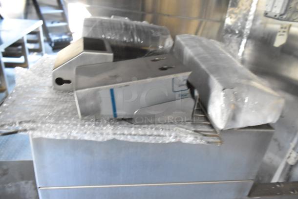 Commercial kitchen equipment, brand new, wrapped in plastic and bubble wrap. Items include stainless steel fixtures.