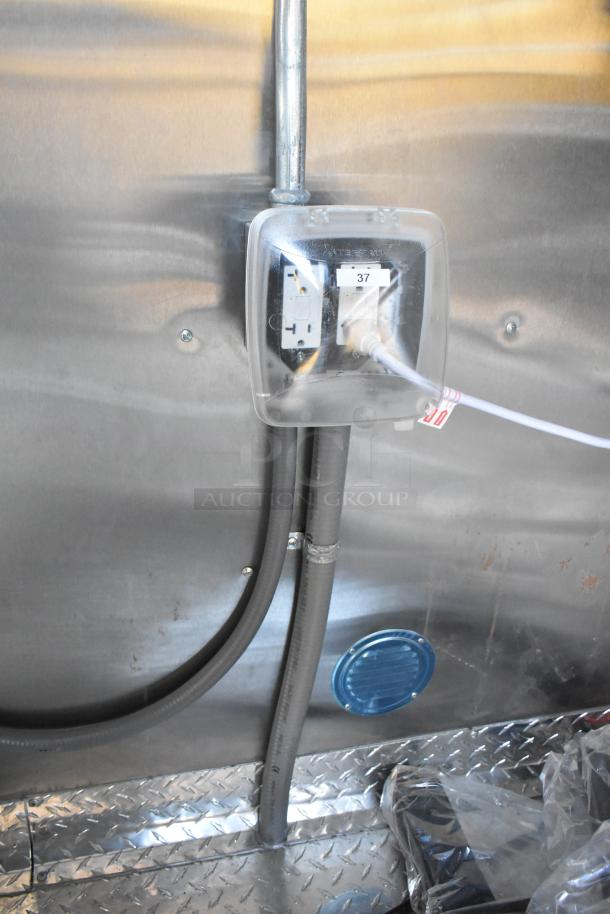 Interior view of Cruising Kitchens 24' fast food trailer showing electrical outlet and piping, with protective cover labeled "37".