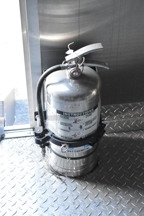 Stainless steel fire extinguisher with instructions and wet chemical label inside 2021 Cruising Kitchens Burger King trailer.