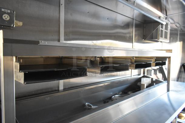 2021 Cruising Kitchens 24' fast food trailer interior, featuring commercial-grade stainless steel fixtures and shelving.