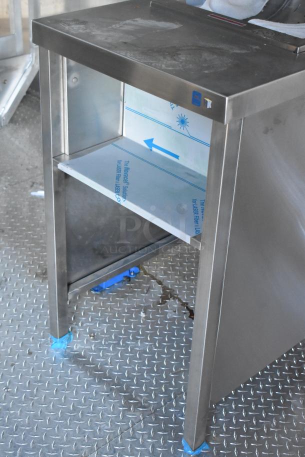 Stainless steel commercial kitchen shelf with protective covering in a 2021 Cruising Kitchens fast food trailer.