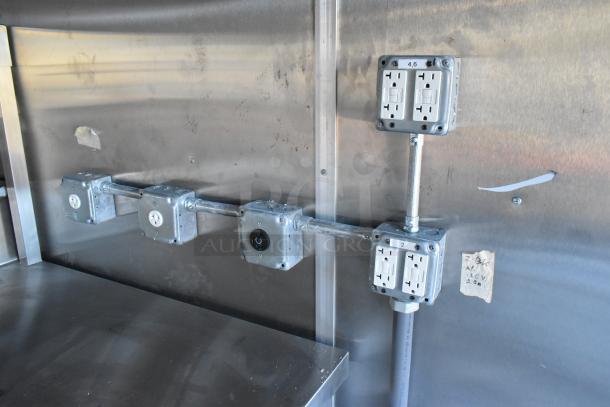 Interior view of a 2021 Cruising Kitchens 24' Burger King fast food trailer. Displays electrical outlets and metal fixtures on a stainless steel wall, indicating commercial-grade wiring.