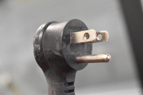 Close-up of a power plug compatible with the 2021 True TSCI-600R-G-PH commercial cooler, showing prongs and wear.