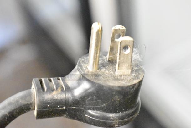 Black power plug for True T-19F freezer, showing three prongs; part of a commercial appliance.
