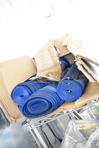 Four rolls of blue material in a damaged cardboard box, with grommets visible on some rolls; marked "3740".