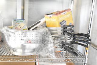 Brand new kitchen items including an 18" magnetic knife rack, Winco ALO-8BH colander, Winco SPBR-604 butter roller, and Vollrath 67810 skillets. Quantity of 14 scratch and dent items on auction.