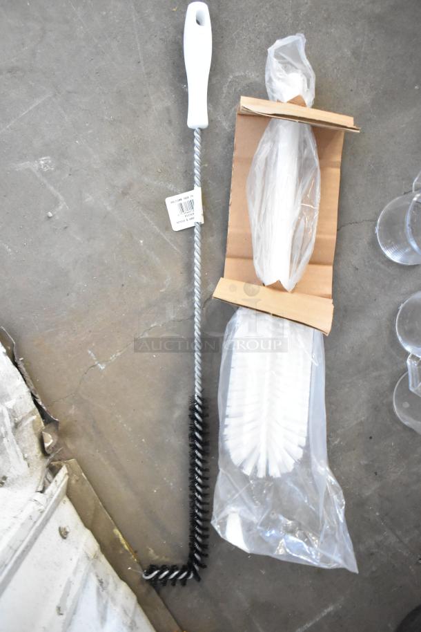 Brand new cleaning brushes with white handles and bristles, scratch and dent condition, includes packaging.