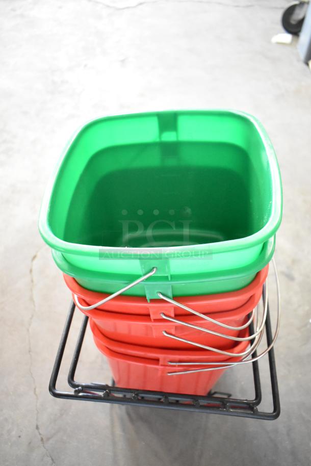 Stack of poly bins: one green on top of four red, with metal handles, placed on a black rack. New condition, minor scratches.