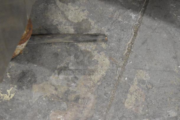 Close-up of a worn and dusty floor beneath a piece of commercial equipment, possibly indicating the wear over time.