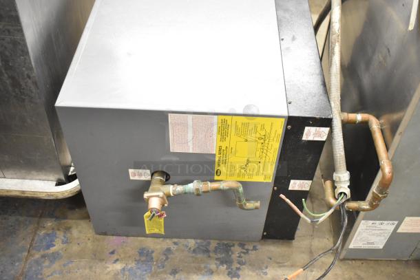 Hatco Imperial Series Commercial Hot Water Booster Heater, gray casing, pipe connections, instruction label visible.