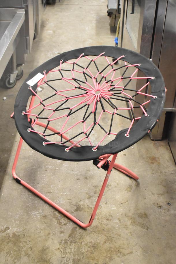 Folding net chair with a pink and black elastic seat design on a pink metal frame, in good condition.