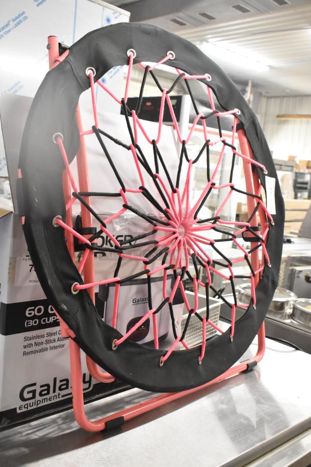 Folding net chair with pink and black netting, circular frame, and metal legs. Appears in excellent condition.