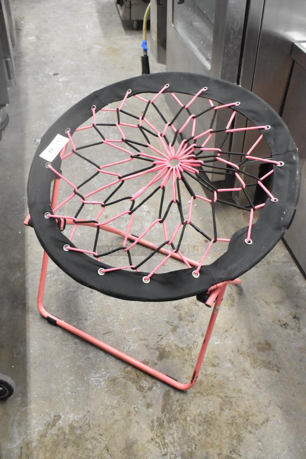 Folding net chair with a pink metal frame and black netting. Excellent condition. Auction label number 77 attached.