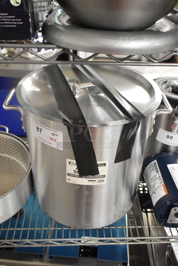 Brand new 471SP40QTHD Choice 40 Qt. aluminum stock pot with lid, taped closed, on metal shelf, labels visible.