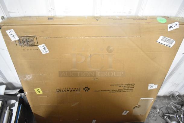 Large cardboard box labeled "Lancaster Table & Seating," containing new unassembled furniture items; box is scratched.