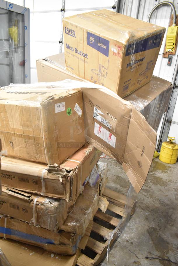 Stack of boxes containing brand new commercial items including Regency Stainless Steel Work Table, Watts Grease Interceptor, and Hatco Infrared Food Warmer. Boxes show signs of wear.