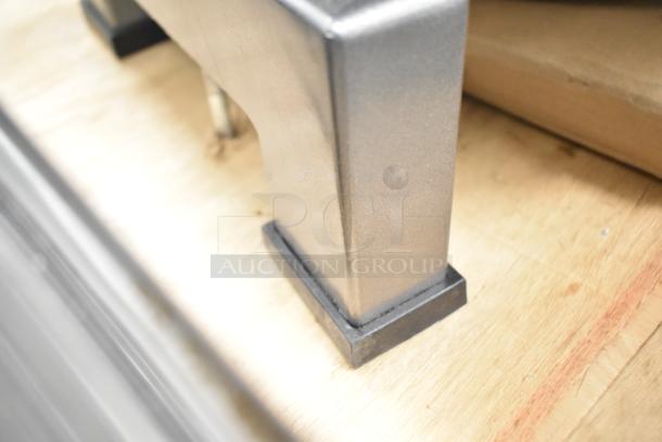 Close-up of the Avantco 177MX10H dough mixer's sturdy metal leg on a wooden surface, showcasing construction details.