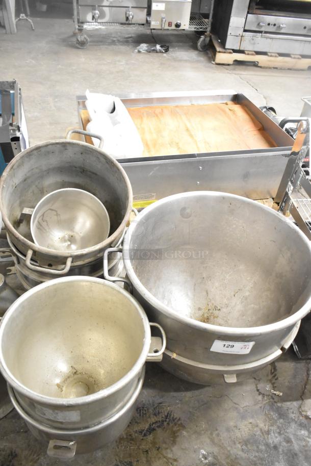6 industrial mixing bowls for mixers, stainless steel, stacked with varying sizes, visible wear. Label: "Lot 129."
