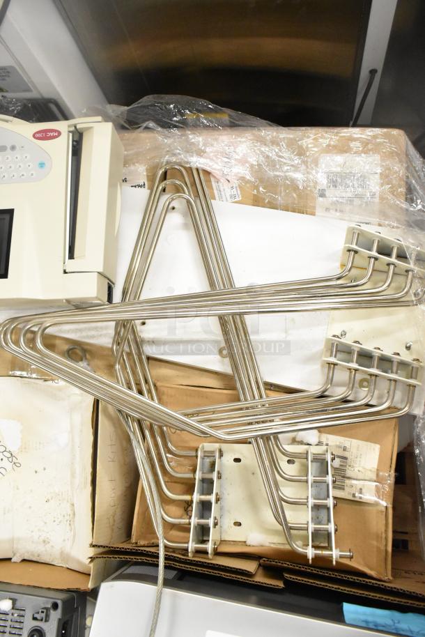 Marquette MAC1200 EKG machine and metal pieces on a table, items for auction. Condition appears used. Various labels visible.