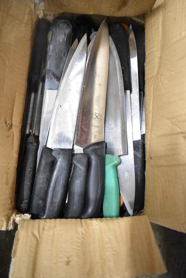 A cardboard box containing 62 sharpened stainless steel knives, including a chef knife with black handles.
