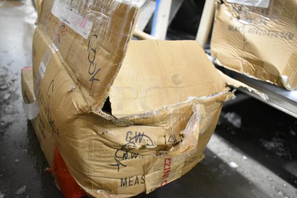 Damaged cardboard box containing 85 sharpened stainless steel knives, including a chef knife. Box shows wear and shipping labels.