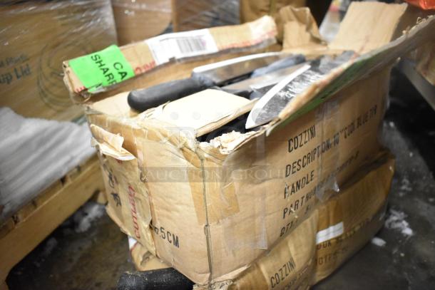 Box of 100 sharpened stainless steel knives, including chef and serrated knives. Visible wear on box. Marked "COZZINI."