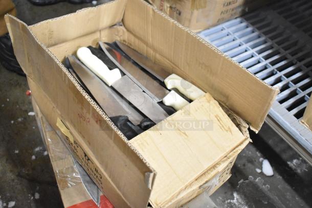 Box of sharpened stainless steel knives, including chef knives, with black and white handles. Slightly worn cardboard box.