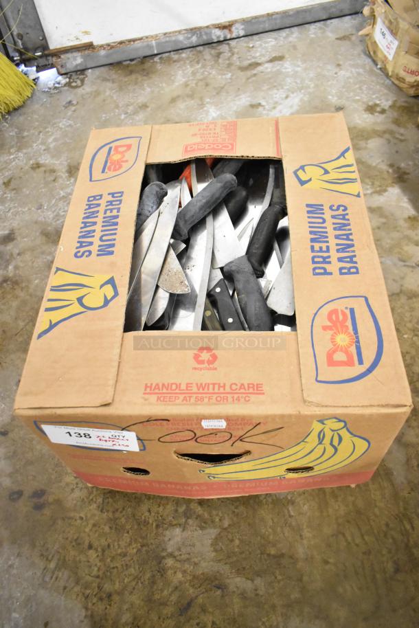 Cardboard box filled with 220 sharpened stainless steel knives, including chef knives, visible in assorted blade and handle styles. Handle With Care label on box.