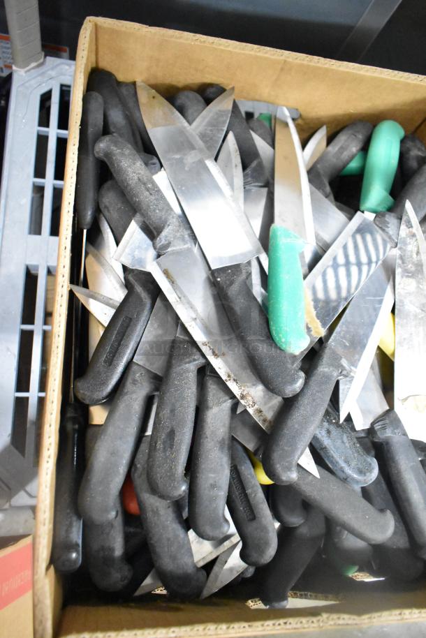 Box of 150 sharpened stainless steel knives with black handles, featuring chef knives. Various conditions visible.