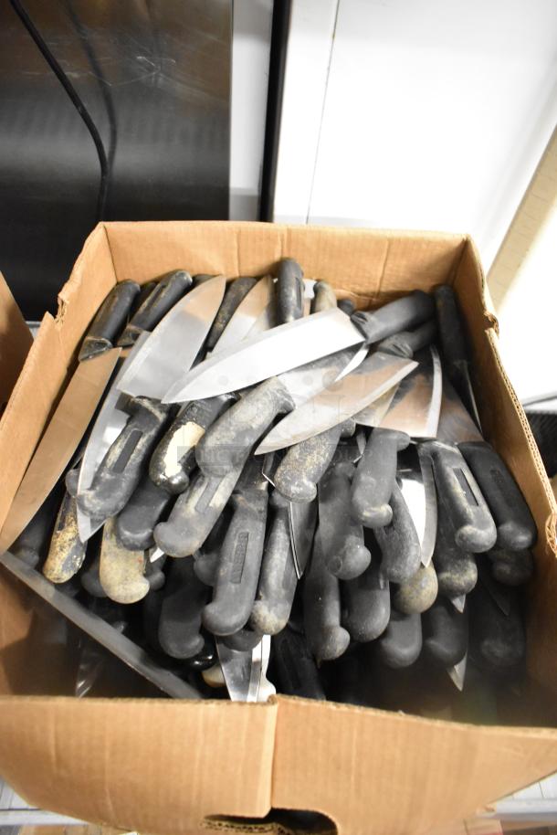 Box of 200 sharpened stainless steel knives, including chef and serrated types, with black handles; auction listing.