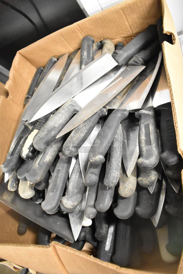 Box of 200 sharpened stainless steel knives, including chef and serrated knives, with black handles. Signs of wear.