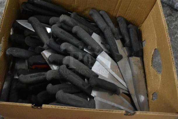 Box of 150 sharpened stainless steel knives, including chef knives, with black handles. Ideal for bulk purchase.