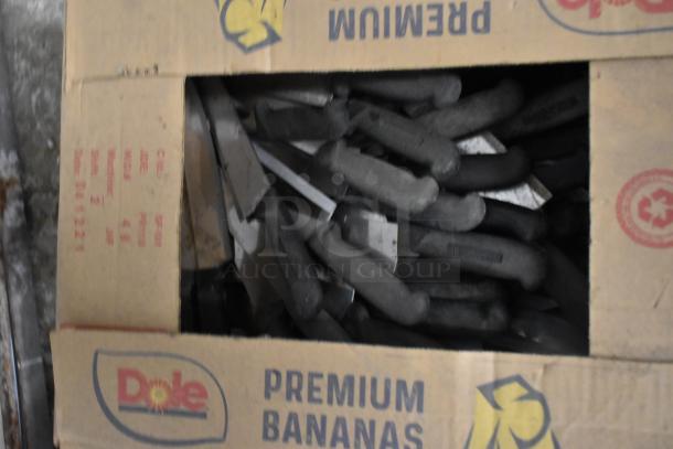 Box of 150 sharpened stainless steel knives including chef knives. Handles are black. Box labeled "Dole Premium Bananas."