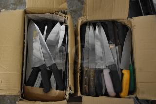 Two boxes containing 150 sharpened stainless steel knives, including chef knives. Handles are varied in color and style.