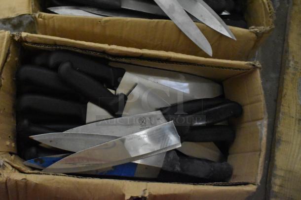 Two boxes of sharpened stainless steel knives with black handles, including chef knives. Visible markings: "Mercer" brand.