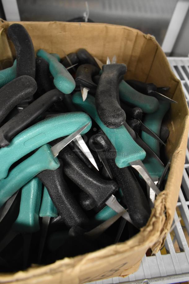 Box of 200 sharpened stainless steel knives, including poultry and paring knives, with black and green handles.
