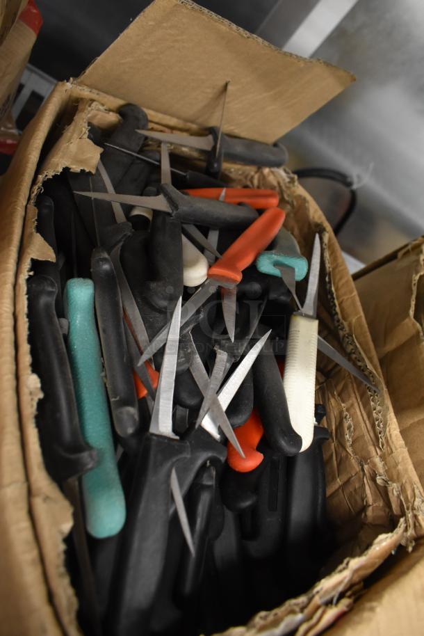 Box of 200 sharpened stainless steel knives, including poultry and paring types, with assorted colored handles.