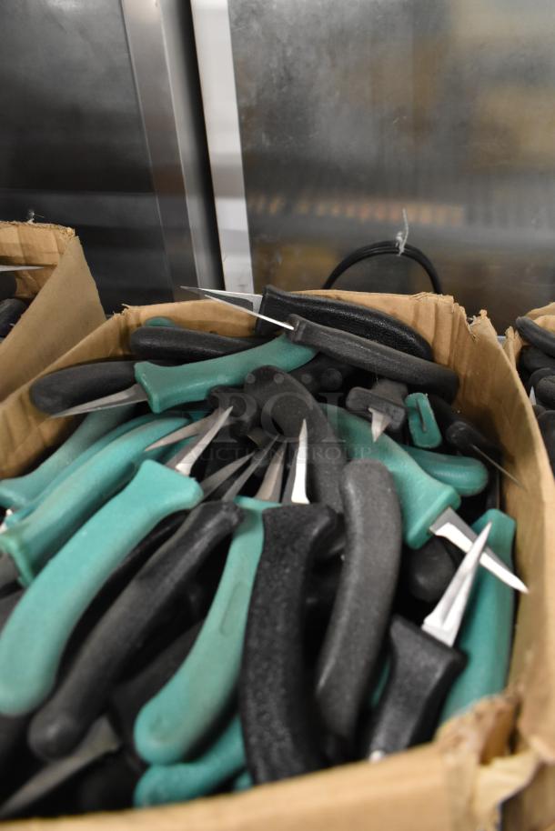 Box of 250 sharpened stainless steel knives with black and green handles, including a poultry knife.