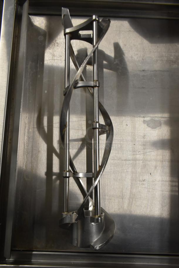 Stainless steel auger from ice cream machine, featuring intricate design, part of auction lot with various machine parts.