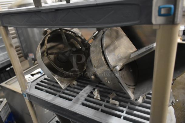 Two Pelican heads with slicing blade and frame on shelf; one missing front piece and blade. Auction item, bid multiplier applies.