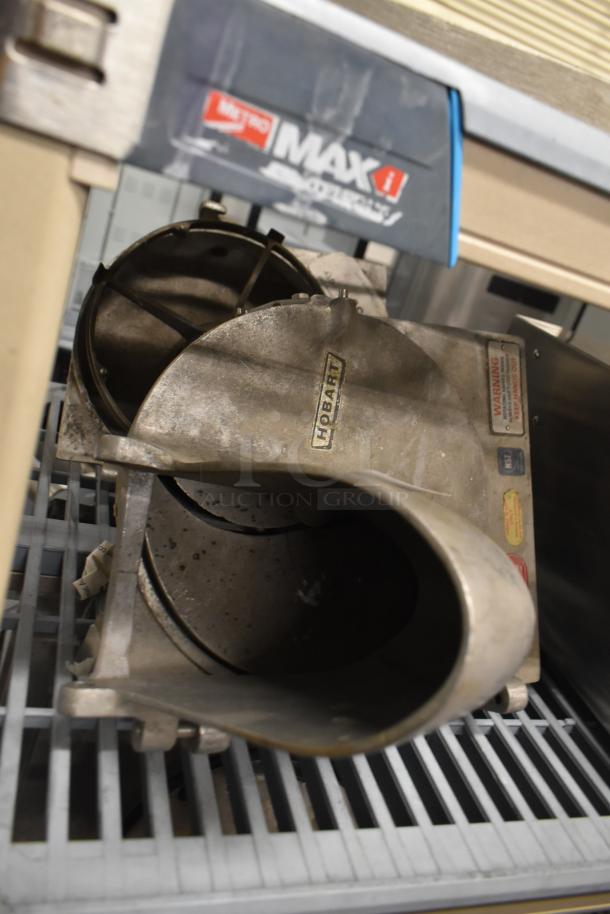 Two Pelican heads with slicing blade and frame, one missing front piece and blade, Hobart brand, visible labels, used condition.