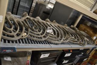 Nine metal paddle attachments for Hobart mixer on a shelf, each tagged, in used condition.